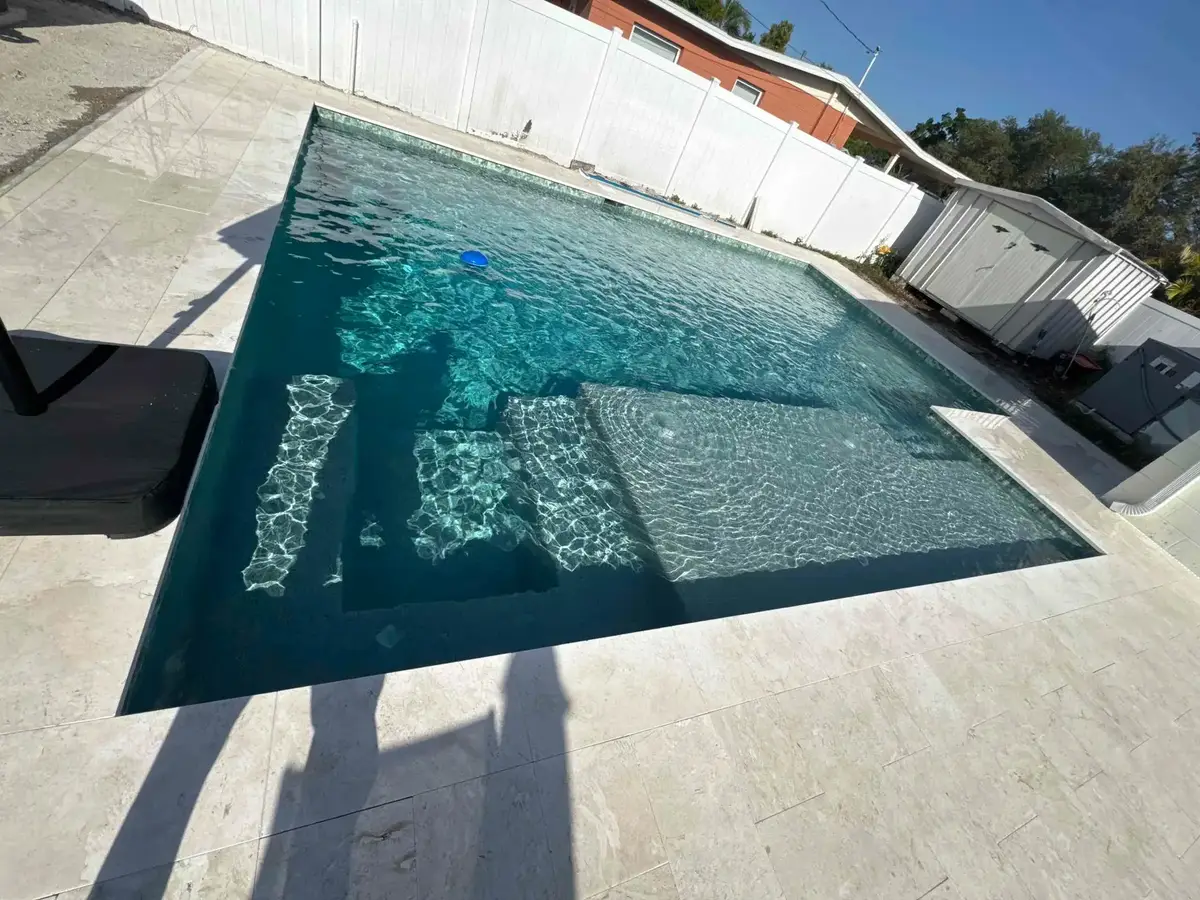 Custom pool with dark pebble finish, long sun shelf, and active water bubbler jets