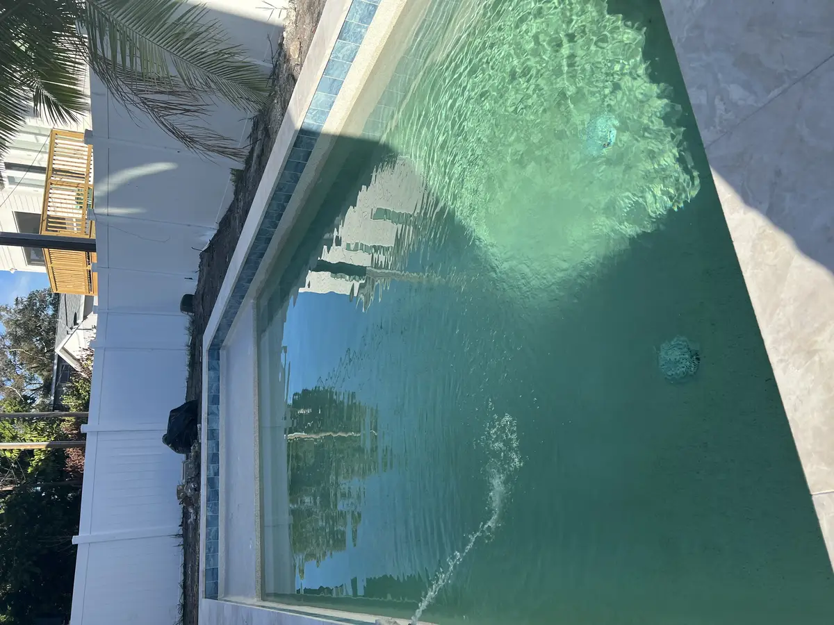 Rectangular pool shell under construction next to a white boundary fence