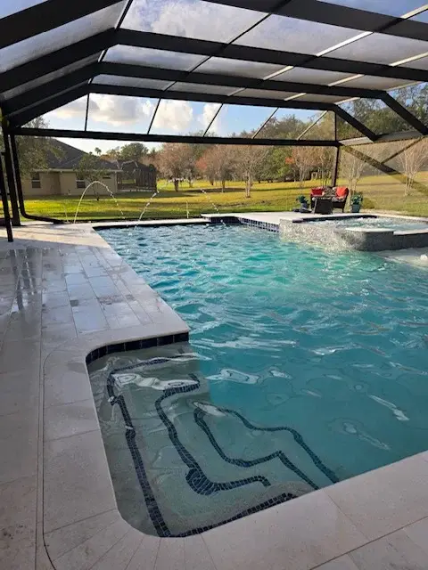 Rectangular pool under screen enclosure with three fountains, travertine, and spa