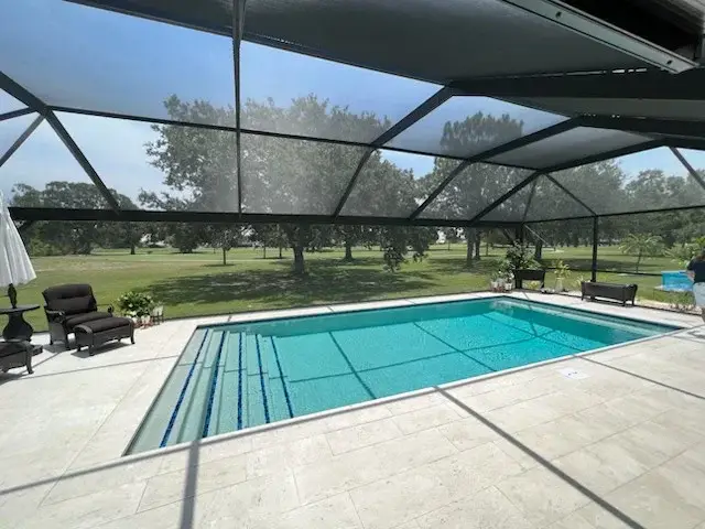 Rectangular pool under screen enclosure with wide steps spanning the near end