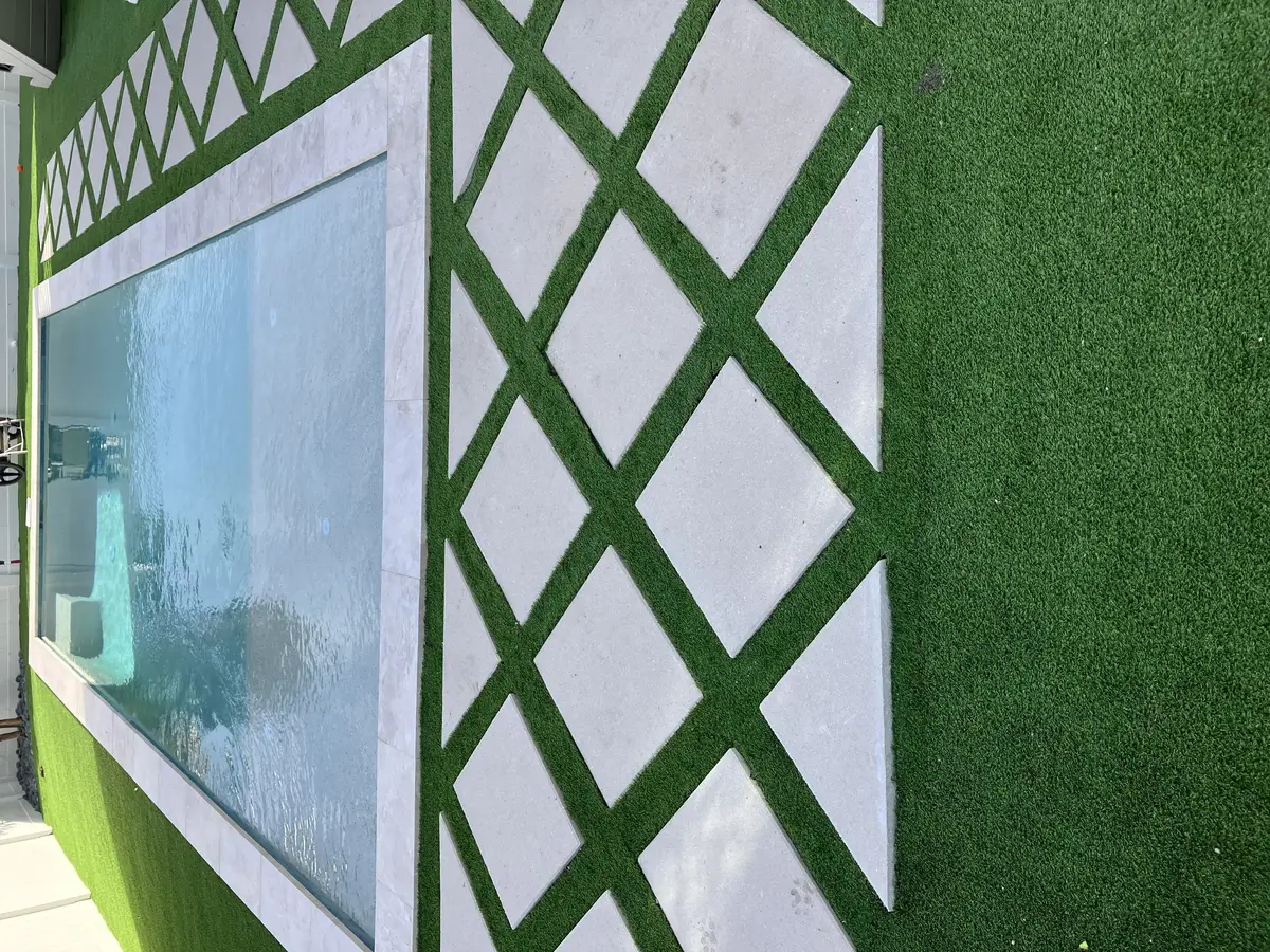 Custom pool deck renovation featuring diamond pavers bordered by artificial turf