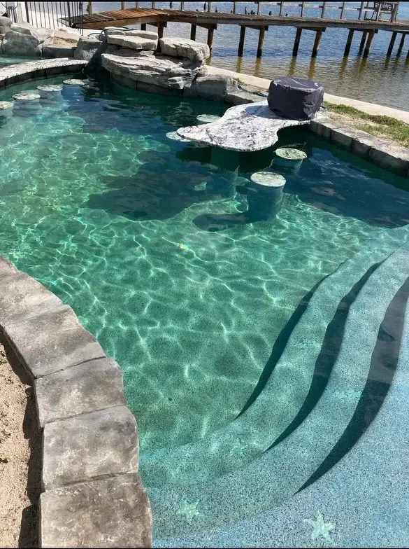 Close-up of submerged stone table and concrete bar stools in clear pool water