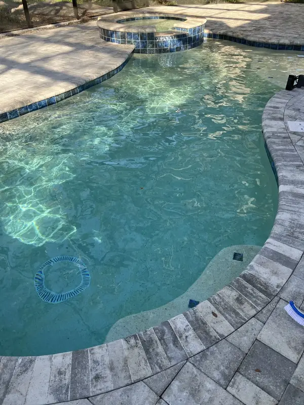 Custom concrete pool and circular spa spillover under a screen enclosure in Clearwater, FL