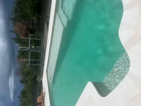 Shimmering turquoise pool with sun shelf overlooking a coastal waterway canal