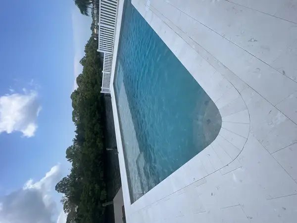 Finished rectangular concrete pool next to a waterway canal with travertine decking