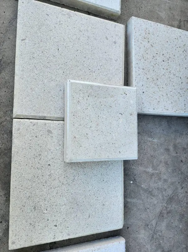 Samples of textured square limerock concrete pavers displayed on concrete