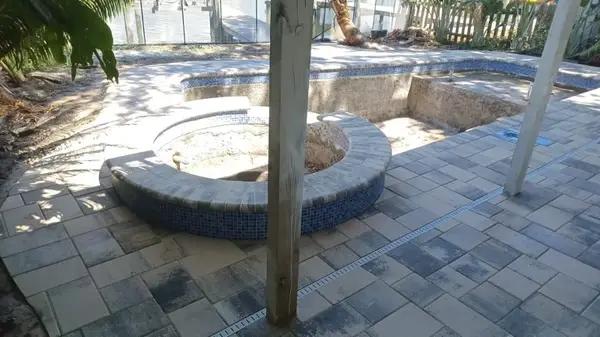 Under-construction custom pool showing grey stone pavers deck and circular spa shell